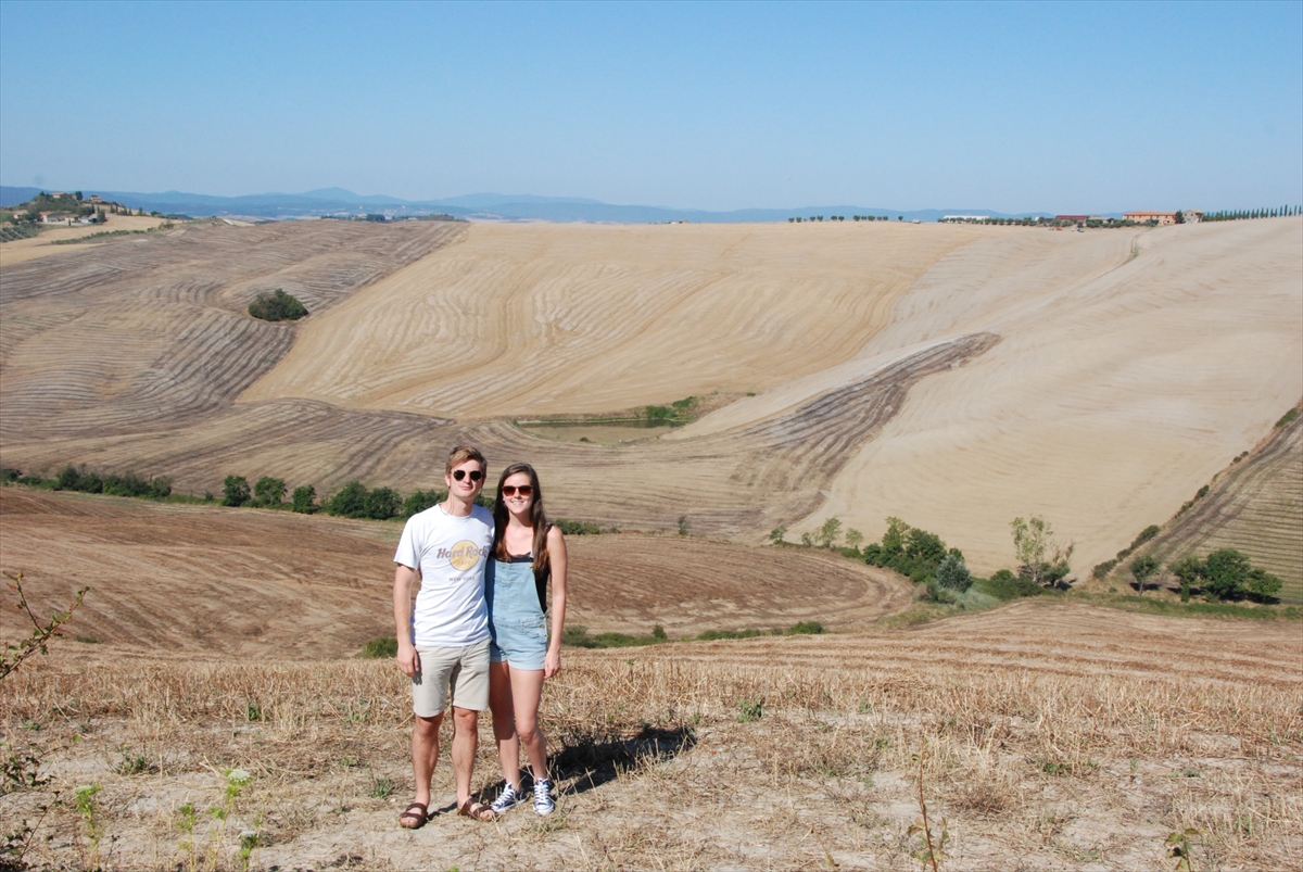 Valerie en Emiel in een heuvelachtig, geoogst landschap in Toscane